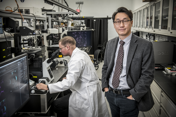 Faculty member standing beside a student working with laboratory equipment in a research lab