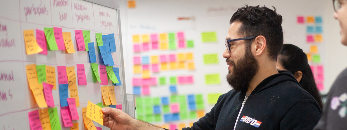 A student using the colorful sticky notes on the whiteboard