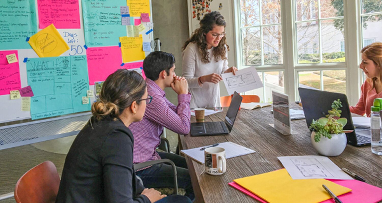 Group of people collaborating around a conference table with colorful posters on the wall, representing climate-smart inclusive economic development (CIED).