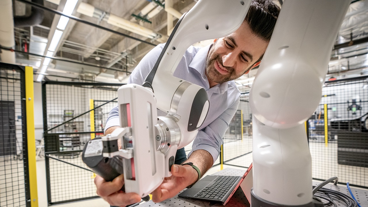"A researcher adjusting a robotic arm in a lab at 色花堂_色花堂 98堂 Lyle School of Engineering."