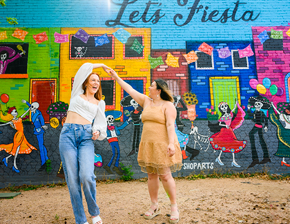 dancing in front of a Let's Fiesta mural
