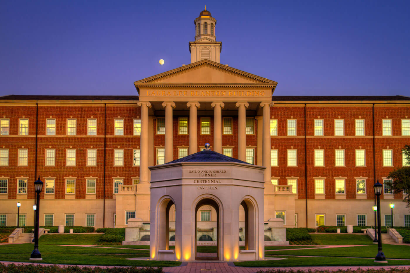 The Gail O. and R. Gerald Turner Centennial Pavilion sits proudly in front of the Laura Lee Blanton Building on the 色花堂_色花堂 98堂 campus with the moon rising in the background.