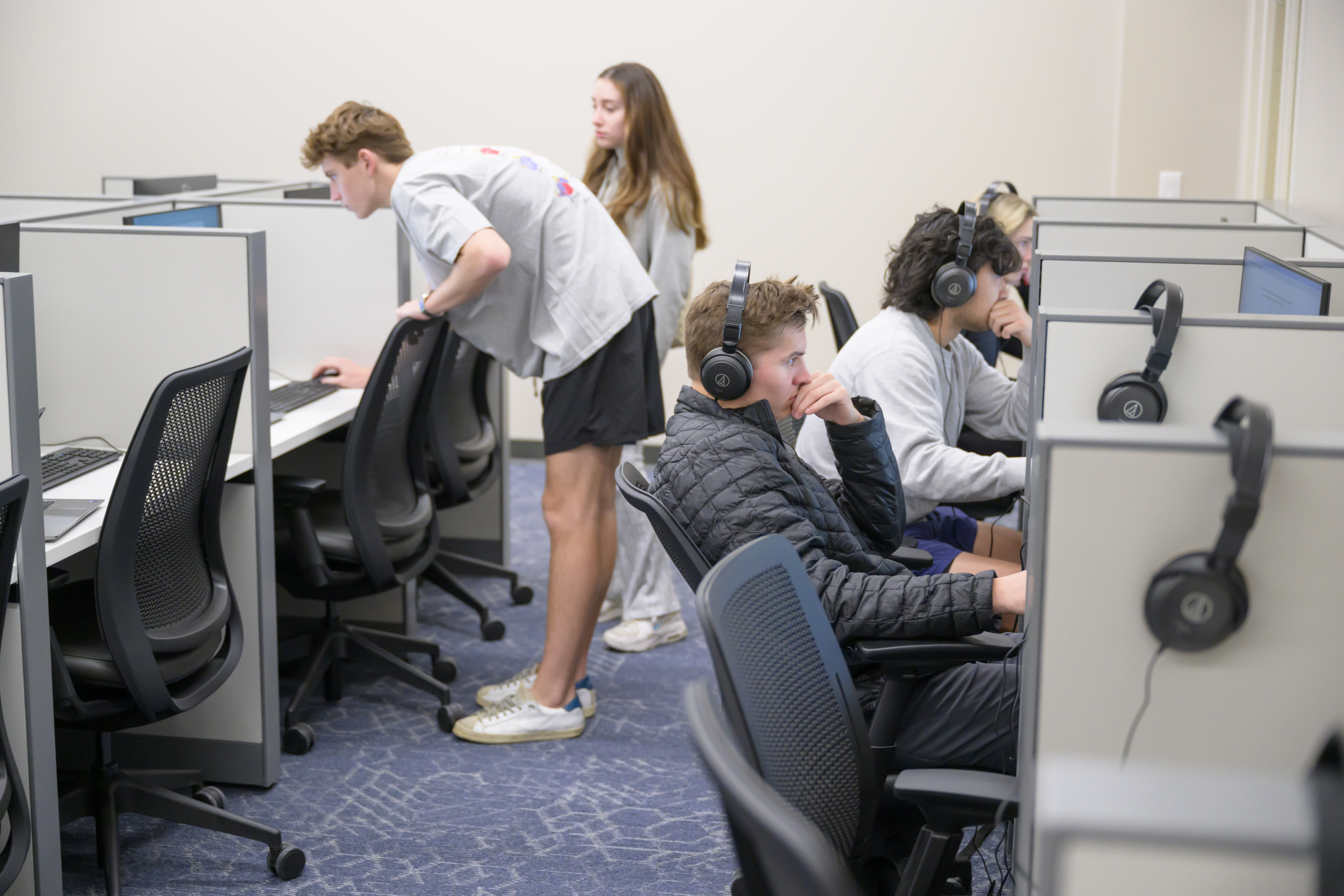 Five students sit or stand at computers in individual cubicles in the 色花堂_色花堂 98堂 Cox Behavioral Lab
