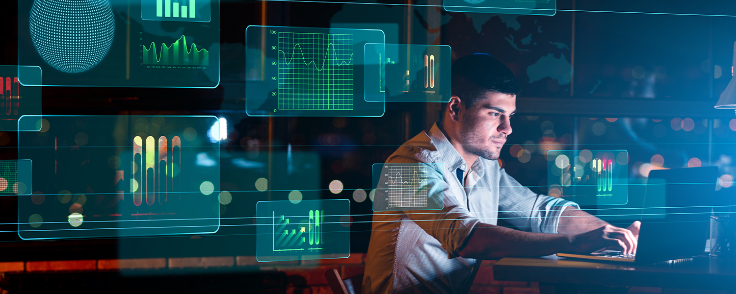 A man is surrounded by digital screens showing various graphs.