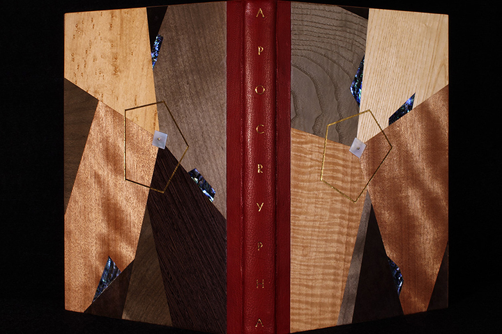 Decorative binding made of various wooden panels. The center of the covers has mother of pearl pinned to it surrounded by a gold pentagon. Spine has title "Apocrypha".