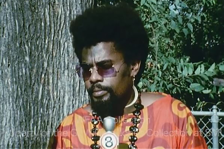 man in a colorful outfit standing by a tree