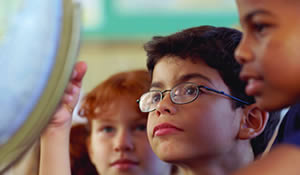 Young students inspect world globe.