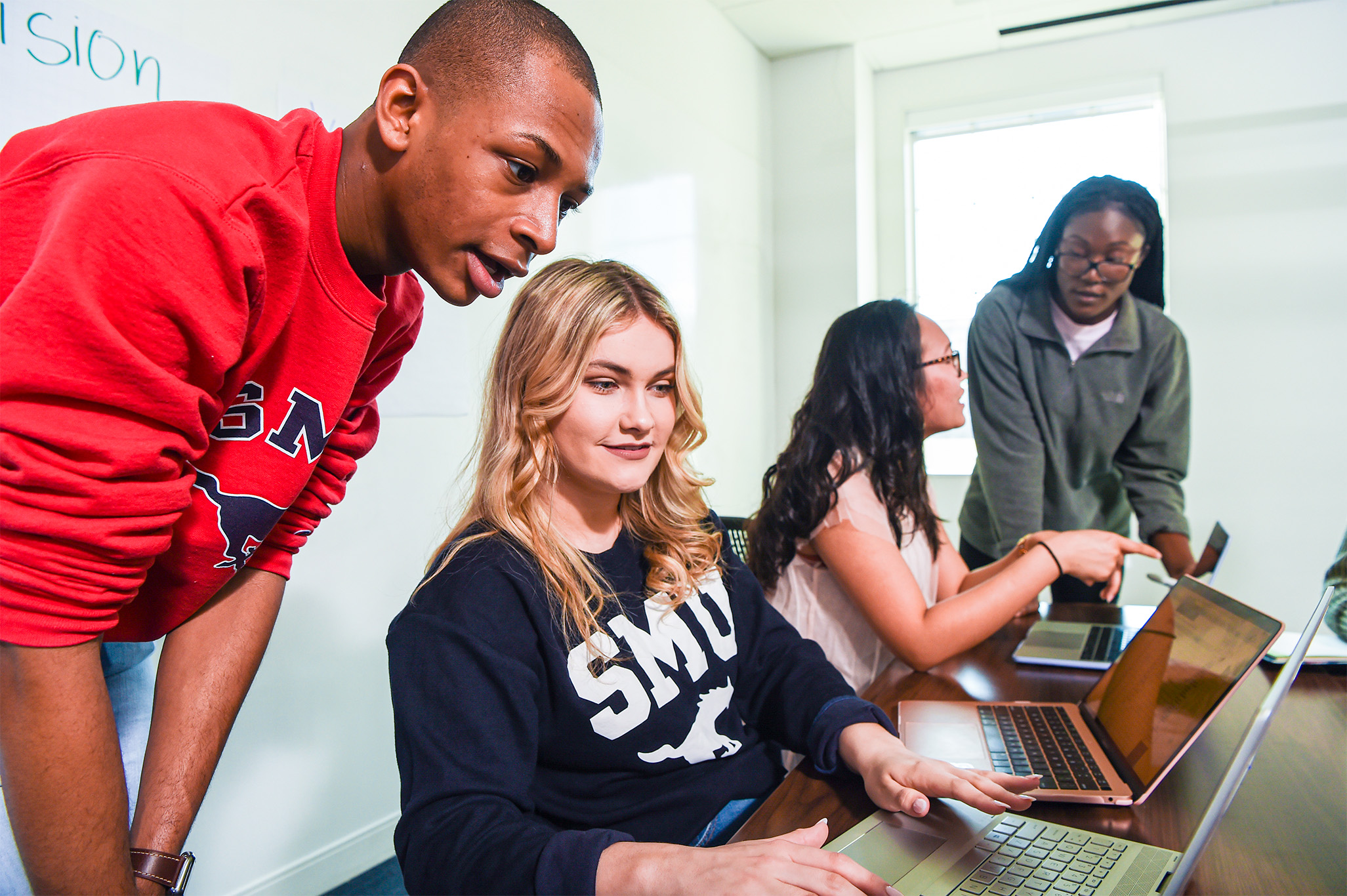 students sitting at table looking at computer and talking