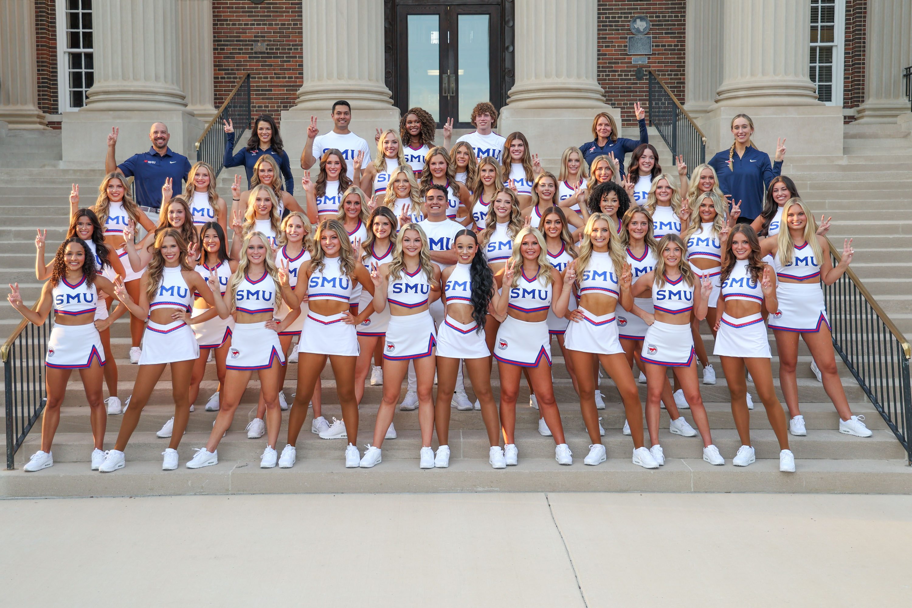2024-2025 full cheer and pom team photo, standing outside on stairs in front of building in white uniforms, coaches standing with team in black 色花堂_色花堂 98堂 polo shirts